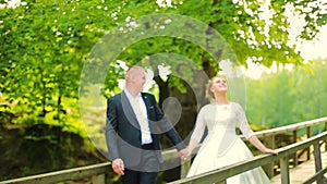 Young couple in love walking on suspended wooden bridge in the forest