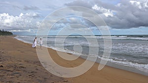 Young couple in love walks on the beach at sunset, holding hands