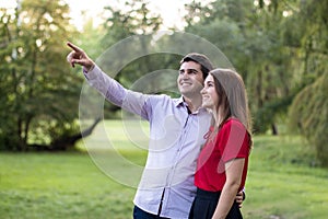 Young couple in love watching birds on trees in the park