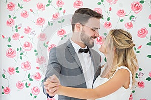 young couple in love Wedding Bride and groom dancing together and looking at each other on roses backdrop . Newlyweds. portrait