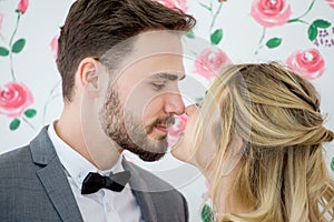 young couple in love Wedding Bride and groom kissing on roses backdrop. Newlyweds. Closeup portrait of a beautiful having a