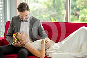 young couple in love Wedding Bride and groom lying down on red sofa together looking at each other . Newlyweds . Closeup portrait