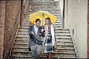 A young couple in love which is talking while descending the stairs in the city during a rainy day. Walk, rain, city, relationship