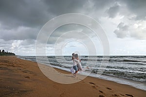 Young couple in love whirling and hugging on tropical ocean beach