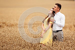 A young couple of lovers woman and man hugging in nature, in a yellow wheat field. The concept of love, good relationships,