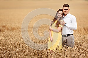 A young couple of lovers woman and man hugging in nature, in a yellow wheat field. The concept of love, good relationships,