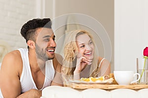 Young Couple Lying In Bed Eat Breakfast Morning With Red Rose Flower, Happy Smile Hispanic Man And Woman