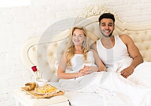 Young Couple Lying In Bed Eat Breakfast Morning With Red Rose Flower, Happy Smile Hispanic Man And Woman