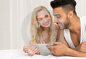 Young Couple Lying In Bed, Happy Smile Hispanic Man And Woman Using Tablet Computer