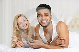 Young Couple Lying In Bed, Happy Smile Hispanic Man And Woman Using Tablet Computer