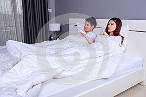 Young couple lying on a bed with remote control of air condition