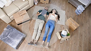 Young couple lying down on the floor of their new apartment