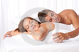 Young couple lying down in white bed