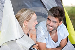 young couple lying at entrance to their tent
