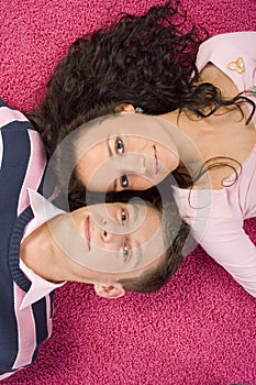 Young couple lying on the pink carpet