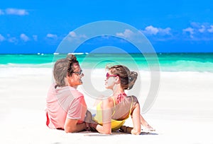 Young couple lying on sand under sunny summer sun