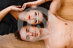 Young couple lying on the wooden floor and looking up. top view