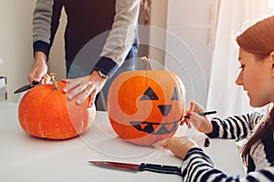 Young couple making jack-o-lantern for halloween on kitchen. Drawing and cutting pumpkin