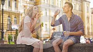 Young couple making soap bubbles, playful romantic mood on date, freedom