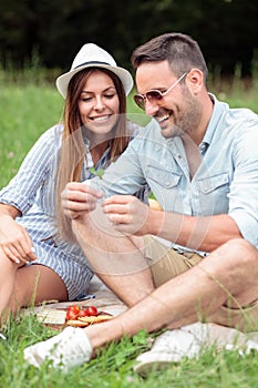 Young couple making a wish after finding four leaf clover while enjoying picnic in a park