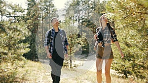 Young couple, man and woman in casual clothes walking in forest on warm day, enjoying nature, talking. Happy