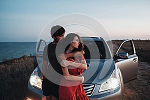 Young Couple Man and Woman Hugging Near Their SUV Car on the Seaside After Sunset, Lovers Enjoying Moment Together
