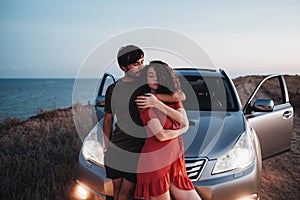 Young Couple Man and Woman Hugging Near Their SUV Car on the Seaside After Sunset, Lovers Enjoying Moment Together