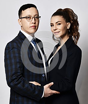 Young couple man and woman in love office workers partners coworkers in official suits stand hugging each other