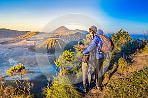 Young couple man and woman meet the sunrise at the Bromo Tengger Semeru National Park on the Java Island, Indonesia