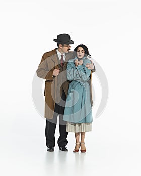 Young couple, man and woman in retro-style clothing, walking. Man is hugging and wrapping the girl in his coat to keep