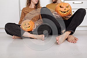 Young couple man and woman sitting on the floor at kitchen at home having fun and preparing for halloween talking laughing