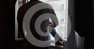 Young couple man and woman sitting on window sill and enjoying old town view. Happy young lovers enjoy time spending