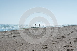 A young couple man and woman walk alone on a deserted beach near the sea. Concept people, landscape, lifestyle