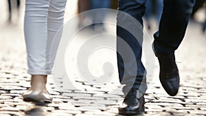 Young couple, a man and a woman, walk around the city, along the pavement. Legs close-up.