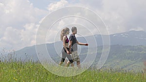 Young couple man and woman walking outdoors in summer mountains.