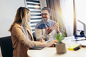 Young couple man and woman working on PC computer together while sitting at table at home