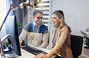 Young couple man and woman working on PC computer together while sitting at table at home