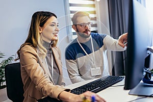 Young couple man and woman working on PC computer together while sitting at table at home