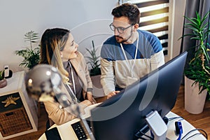 Young couple man and woman working on PC computer together while sitting at table at home