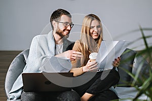 Young couple manages finances with laptop, looking through their bank accounts in the living room on the sofa