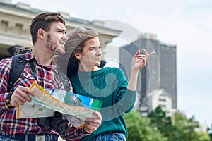 Young couple with a map in the city. Happy tourists sightseeing city with map