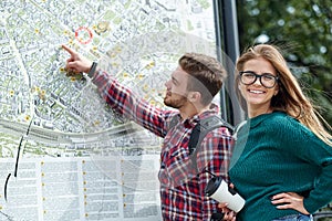 Young couple with a map in the city. Happy tourists sightseeing city with map
