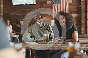 Young Couple Meeting In Sports Bar Enjoying Drink Before Game