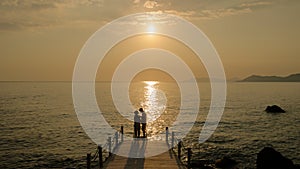 Young couple men and women on a wooden pier watching sunset during vacation in Turkey
