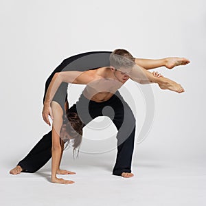 Young couple of modern ballet dancers posing on clear studio background