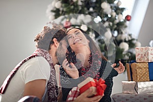 A young couple in moments of closeness at home giving Xmas presents. Christmas, relationship, love, together