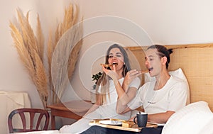 Young couple in the morning having romantic breakfast in bed in Valentines day as happy relationships