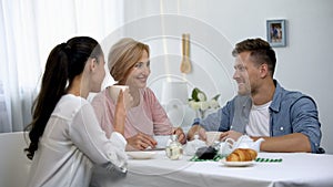 Young couple and mother-in-law drinking tea, sincerely laughing, time together photo