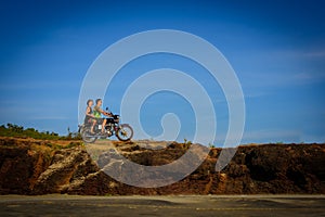 Young couple on a motorcycle on on rocky ground. Happy guy and girl travelling on a motorbike