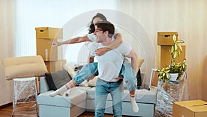 Young couple move into new apartment. Man hold woman in his back and spin her around. Couple dancing in middle of room